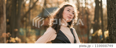 Banner portrait woman walking in autumn park, happy mood and fashion style trend and curly long brown hair copy space. Fall season and pretty female portrait copy space. Millennial generation concept Banner portrait woman walking in autumn park, happy mood and fashion style trend and curly long brown hair copy space. Fall season and pretty female portrait copy space. Millennial generation concept 110008749