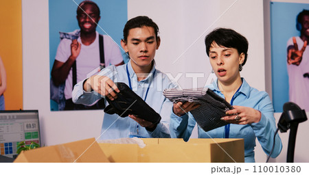 Diverse store managers preparing packages for shipping, putting stylish clothes in carton boxes in modern boutique. Employees working at clients orders, discussing delivery details in shopping mall Diverse store managers preparing packages for shipping, putting stylish clothes in carton boxes in modern boutique. Employees working at clients orders, discussing delivery details in shopping mall 110010380