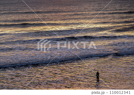 日の出の反射で黄金色に染まる海岸【夜明けの太公望】 110012341