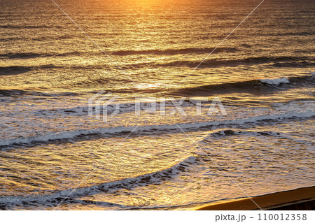 日の出の反射で黄金色に染まる海原 110012358