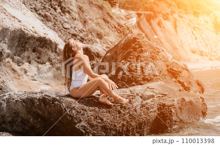 Woman travel sea. Happy tourist in white bikini enjoy taking picture outdoors for memories. Woman traveler posing on the beach at sea surrounded by volcanic mountains, sharing travel adventure journey 110013398