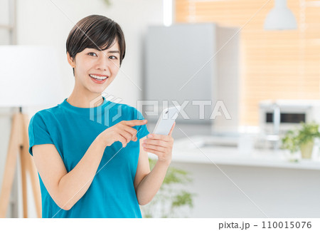 キッチンでスマホを操作する主婦。 キッチンでスマホを操作する主婦。 110015076