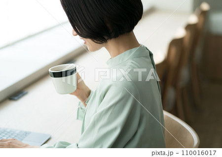 コーヒーを飲みながら仕事をする女性 110016017