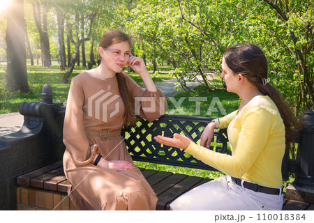 Two girls talking in the park Two girls talking in the park 110018384