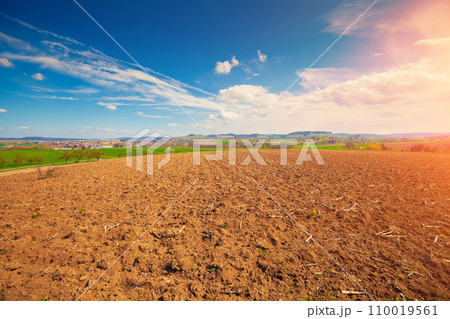 Arable field with beautiful sky and village on a horizon. Springtime 110019561