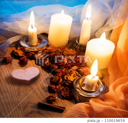 Candles and dried rosebuds on the table 110019659