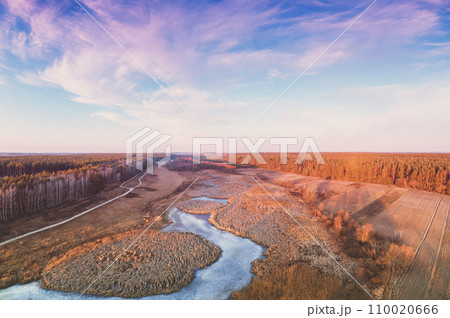 Aerial view of the countryside and frozen brook in the evening at sunset light. Beautiful nature landscape with cloudy sky. Scenic landscape Aerial view of the countryside and frozen brook in the evening at sunset light. Beautiful nature landscape with cloudy sky. Scenic landscape 110020666