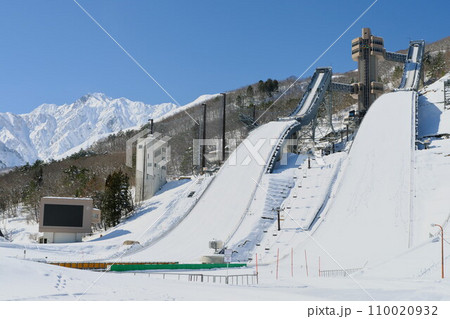 信州白馬村白銀のジャンプ台と北アルプス五竜岳青空に映える 110020932
