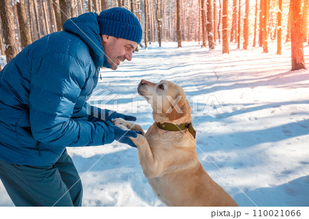 Man and dog are best friends. Man plays with a dog in a snowy forest on a winter sunny day 110021066