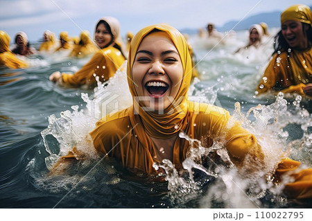 Smiling Muslim woman with hijab joyfully enjoys a fully clothed bath in the sea 110022795