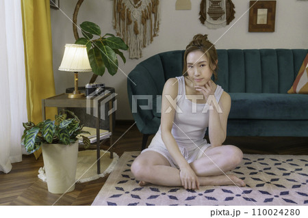 リビングの床に座る若い茶髪の女性のポートレート リビングの床に座る若い茶髪の女性のポートレート 110024280