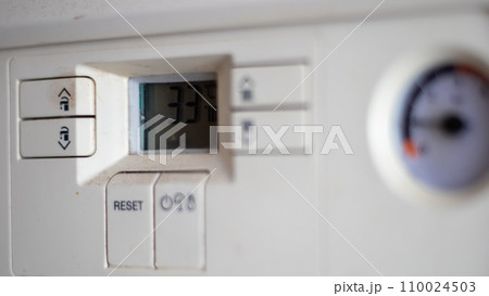 Gas pressure meter on the panel of the heating gas boiler. Symbolic image of the heating season at home. Dial and pressure gauge on combi boiler. Hot water and heating. Boiler accessories 110024503