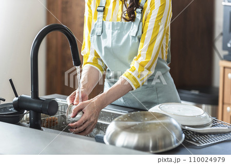 食器を洗うエプロン姿の女性 110024979