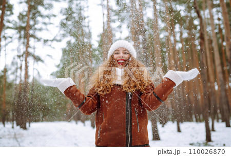 Beautiful woman standing among snowy trees and enjoying first snow. Holidays, rest, travel concept. Beautiful woman standing among snowy trees and enjoying first snow. Holidays, rest, travel concept. 110026870