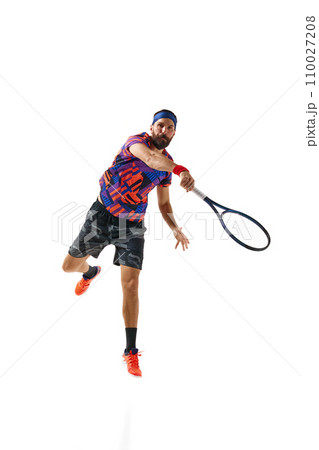 Bearded young man in colorful uniform raining, playing tennis hitting ball with racket isolated over white studio background. Bearded young man in colorful uniform raining, playing tennis hitting ball with racket isolated over white studio background. 110027208