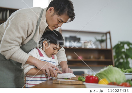 料理をする親子　野菜を切る男の子に手を添える父親 110027458