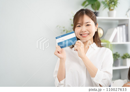 貯金通帳を手に笑顔の女性 110027633