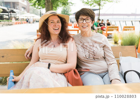 Happy mature mother and her adult daughter enjoying in conversation while spending Mother's day together in a cafe Happy mature mother and her adult daughter enjoying in conversation while spending Mother's day together in a cafe 110028803