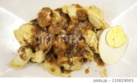 Close up of Batagor siomay Bandung popular street food from Bandung, Indonesia, consist of tofu, fish cake, boiled potato and egg, with peanut sauce. Close up of Batagor siomay Bandung popular street food from Bandung, Indonesia, consist of tofu, fish cake, boiled potato and egg, with peanut sauce. 110029003