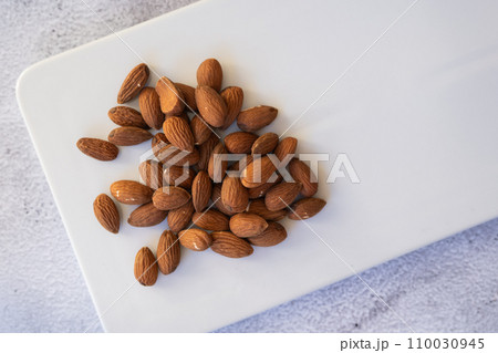 Almonds on a white plate close-up. 110030945