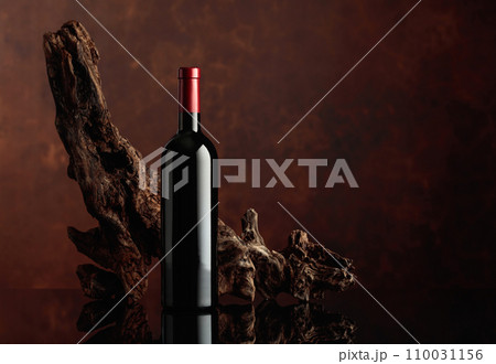 Bottle of red wine with an old weathered snag. 110031156
