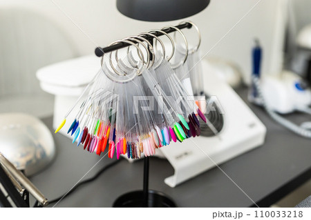 Collection of nails color polish samples. A palette of nail designs of different colors with gel polish. Transparent tips with nail polish samples. Demonstration fan-shaped palette of color shades. 110033218