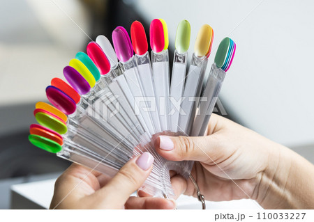 Collection of nails color polish samples. A palette of nail designs of different colors with gel polish. Transparent tips with nail polish samples. Demonstration fan-shaped palette of color shades. 110033227