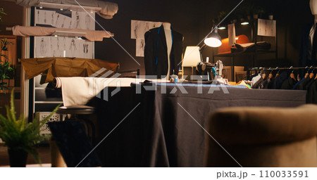 Empty sewing shop with instruments, handcrafting and textile industry atelier with tools and sewing machines. Fashion workshop with clothing sketches and craftsmanship equipment. 110033591