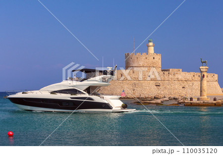 Old stone lighthouse illuminated by the sun at Fort St. Nicholas in Rhodes. Old stone lighthouse illuminated by the sun at Fort St. Nicholas in Rhodes. 110035120
