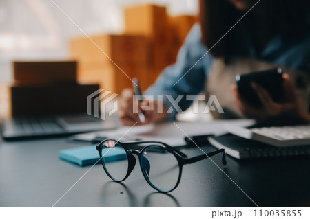Startup small business entrepreneur or freelance Asian woman using a laptop with box, Young success Asian woman with her hand lift up, online marketing packaging box and delivery, SME concept. 110035855