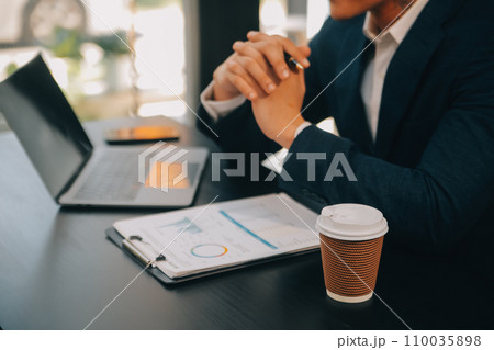 Financial analysts analyze business financial reports on a digital tablet planning investment project during a discussion at a meeting of corporate showing the results of their successful teamwork. 110035898