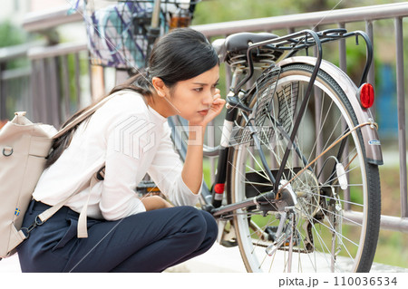 自転車(ママチャリ)の故障に困る若い女性 自転車(ママチャリ)の故障に困る若い女性 110036534