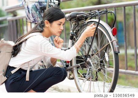自転車(ママチャリ)の故障に困る若い女性 自転車(ママチャリ)の故障に困る若い女性 110036549