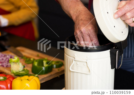 Midsection of caucasian senior man preparing food, composting vegetable waste in kitchen Midsection of caucasian senior man preparing food, composting vegetable waste in kitchen 110039159