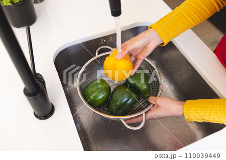 High angle midsection of biracial woman washing vegetables in kitchen sink at home High angle midsection of biracial woman washing vegetables in kitchen sink at home 110039449