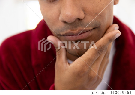 Biracial man touching his face in bathroom at home 110039561