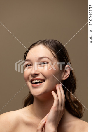 Caucasian woman with brown hair wearing natural makeup on beige background, copy space 110040158