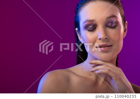 Caucasian woman wearing purple eye shadow on purple background, copy space Caucasian woman wearing purple eye shadow on purple background, copy space 110040235