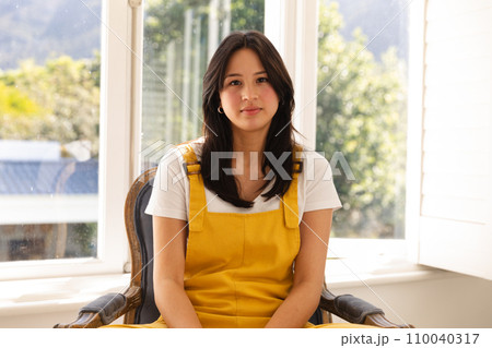 Focused biracial teenage girl having video call sitting in sunny room listening 110040317