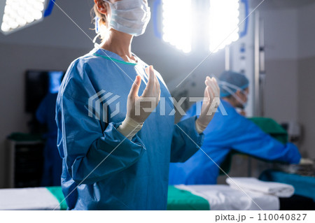 Caucasian female doctor with face mask and protective gloves in hospital operating room Caucasian female doctor with face mask and protective gloves in hospital operating room 110040827