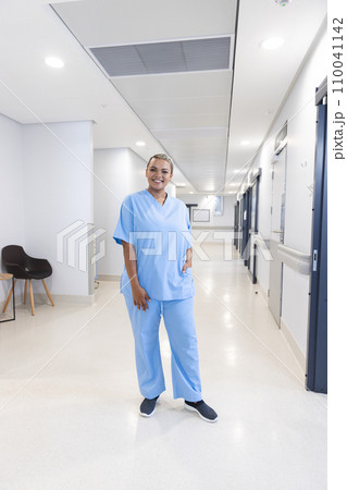 Portrait of happy biracial female doctor wearing scrubs in corridor at hospital, copy space Portrait of happy biracial female doctor wearing scrubs in corridor at hospital, copy space 110041142