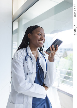Happy african american female doctor talking on smartphone in hospital room 110041436