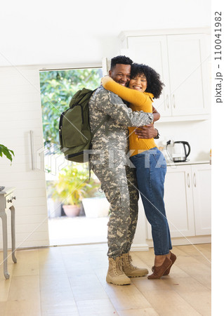 Happy african american male soldier embracing wife at home, copy space 110041982