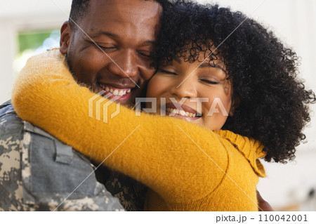 Happy african american male soldier embracing wife at home 110042001