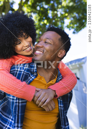 Happy african american couple riding piggyback in sunny garden, copy space Happy african american couple riding piggyback in sunny garden, copy space 110042185