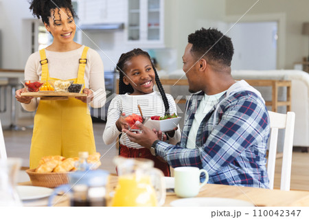 Happy african american family bringing fresh fruits on table in dining room at home, copy space 110042347