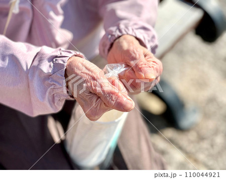 ビニール袋を開けようとする高齢女性の手元 ビニール袋を開けようとする高齢女性の手元 110044921