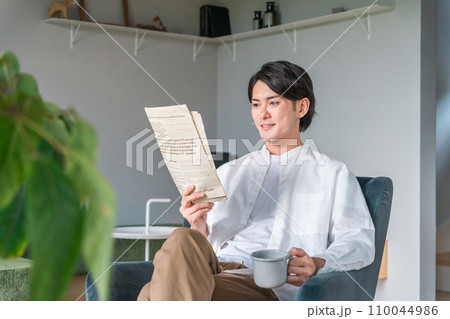 朝コーヒーを飲みながら英字新聞を読む日本人男性（日曜日・リラックス） 110044986