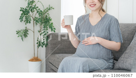 家のソファでホットドリンクを飲む妊婦の女性・マタニティ・プレママ 家のソファでホットドリンクを飲む妊婦の女性・マタニティ・プレママ 110046067