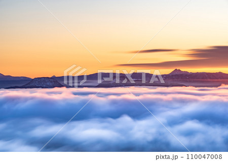 朝焼けの空の下、雲の向こうに遠くの山の稜線。 朝焼けの空の下、雲の向こうに遠くの山の稜線。 110047008